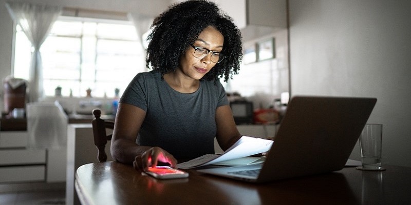 Empreendedora negra olhando para o computador lendo sobre o que montar com 5 mil reais