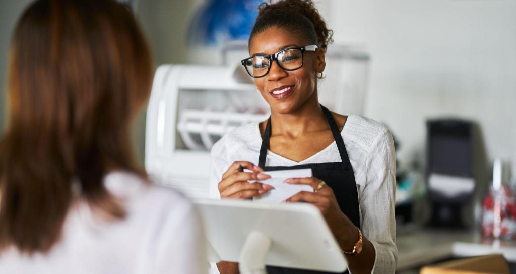 Mulher empreendedora negra de óculos e avental atendendo cliente em balcão de loja, representando o perfil do empreendedorismo feminino no Brasil.