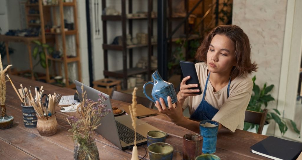 Dona de pequeno negócio criativo produzindo conteúdo para redes sociais como parte do plano de marketing do seu ateliê artesanal.