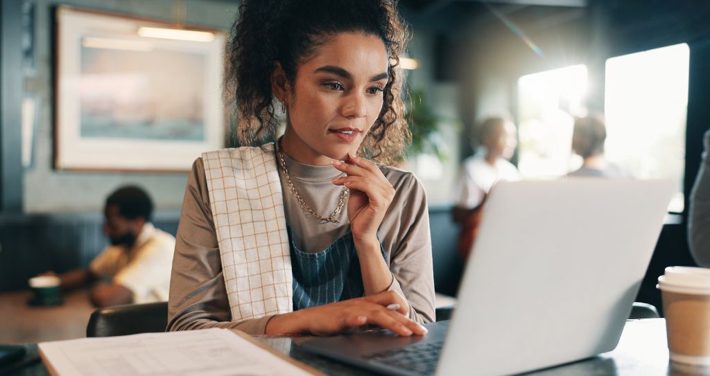 Mulher empreendedora desenvolvendo um plano de marketing em um ambiente de café, focada no planejamento estratégico do seu negócio.