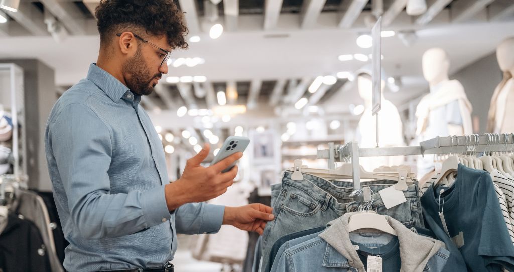 Homem analisando roupas em loja, pensando em ideias de kits e promoções do que vender no Dia dos Pais para atrair mais clientes.