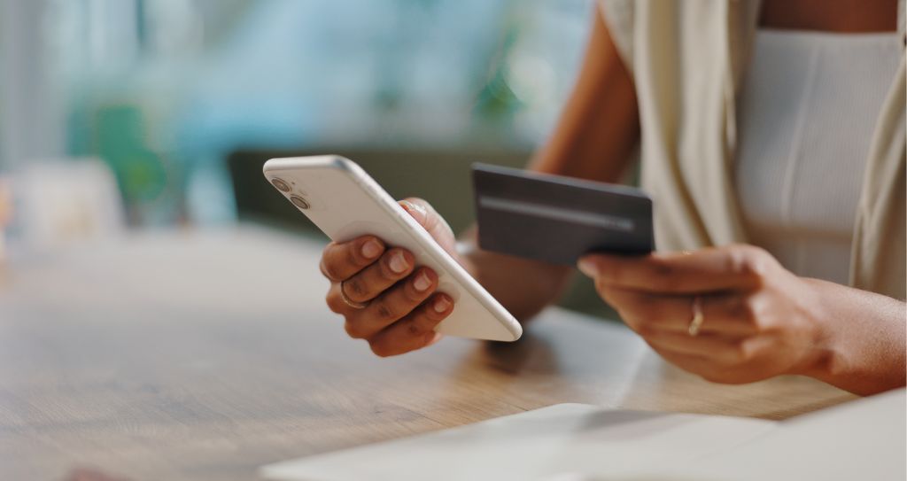 Pessoa fazendo compra online com celular e cartão de crédito, momento em que o gateway de pagamento garante segurança e agilidade na transação.