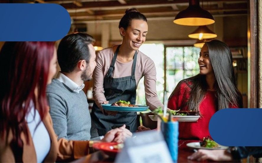 Uma funcionária sorrindo entregando os pedidos para três clientes em um restaurante.