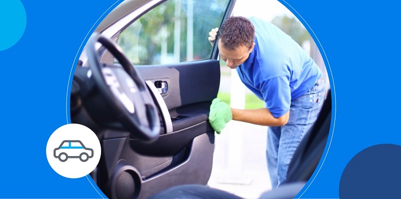 Homem de camisa azul faz limpeza no interior da porta de carro de cliente em lava rápido.