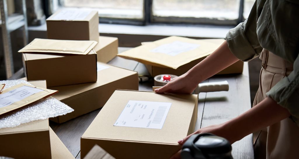 Alt: Pessoa organizando pacotes para envio ou devolução, representando a etapa operacional da logística reversa em negócios online.
