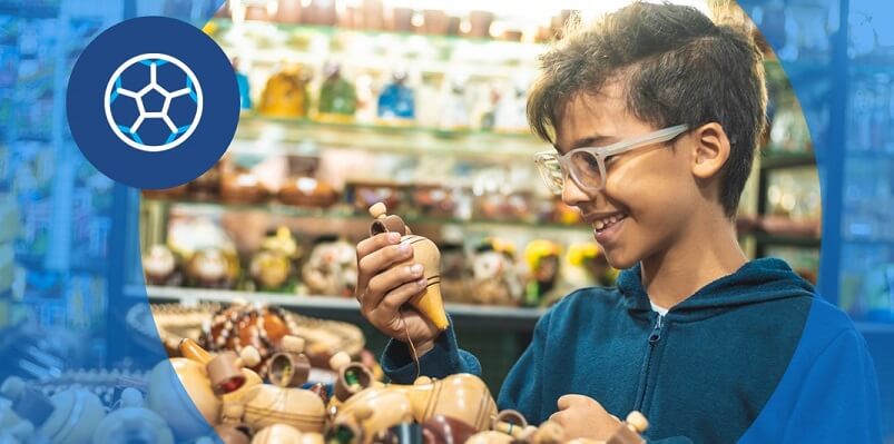 Menino de óculos e cerca de 10 anos observa pião em loja de brinquedos no Dia das Crianças.