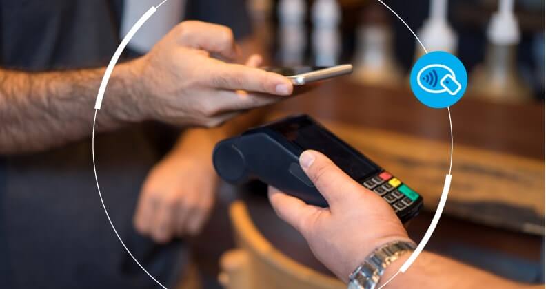 Mão de homem aproxima celular de maquininha com tecnologia NFC para realizar pagamento.