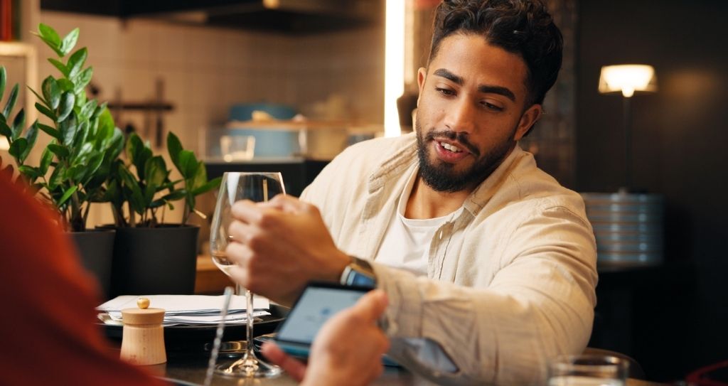 Homem usando smartwatch para pagamento por aproximação em restaurante, exemplificando como o NFC pode ser utilizado em dispositivos portáteis para facilitar os pagamentos.