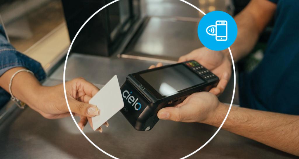 Pessoa realizando pagamento por aproximação com cartão em uma maquininha Cielo, ilustrando o que é NFC.