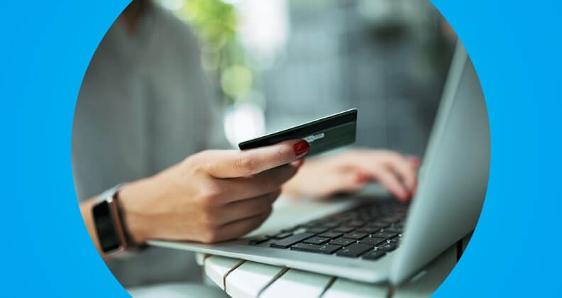 Cliente em frente ao computador segurando cartão fazendo um compra via e-commerce, utilizando um intermediador de pagamento