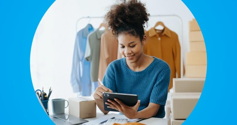 Empreendedora de blusa azul consulta no tablet os kpis de vendas da sua loja de roupas.