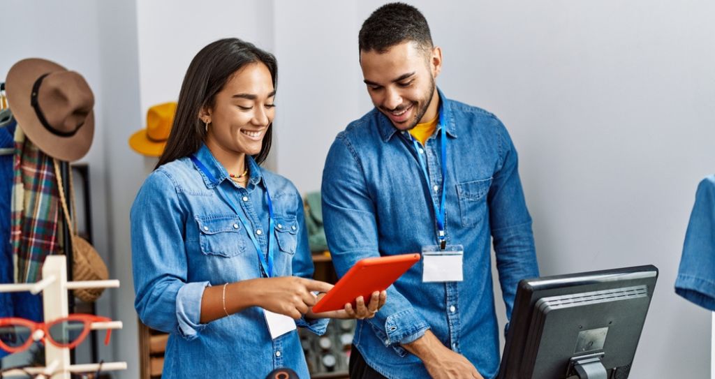 Empreendedores com tablet em loja, analisando os melhores produtos para vender na internet.