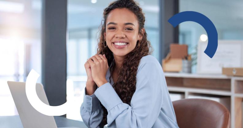 Mulher de camisa azul sentada em uma mesa com um laptop em um escritório.