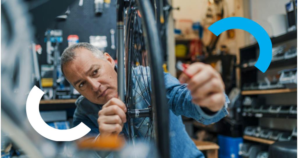 Microempreendedor desempenhando uma atividade do MEI, consertando uma roda de bicicleta em uma oficina.