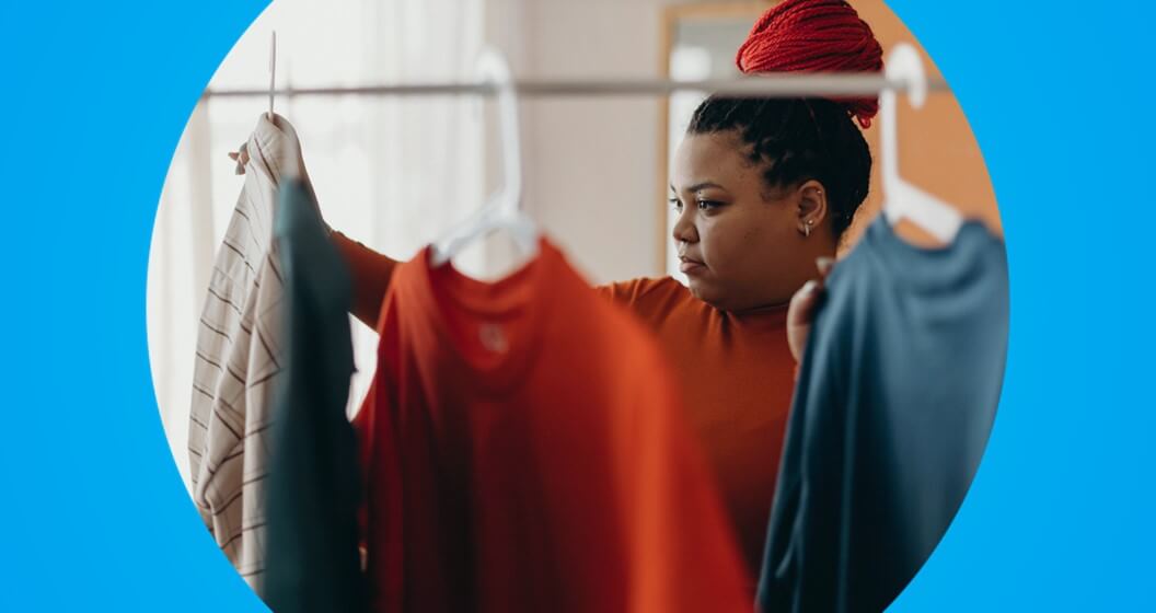 Mulher no projeto Asmara olhando roupas em um cabide. 