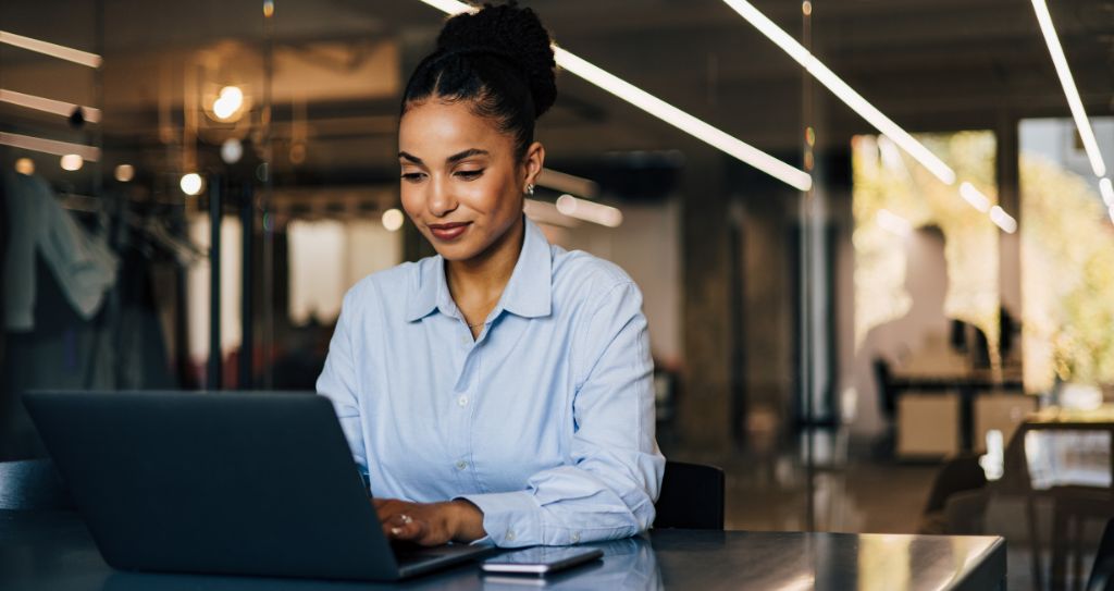 Empresária analisando dados no notebook de uma pesquisa de mercado em ambiente corporativo.