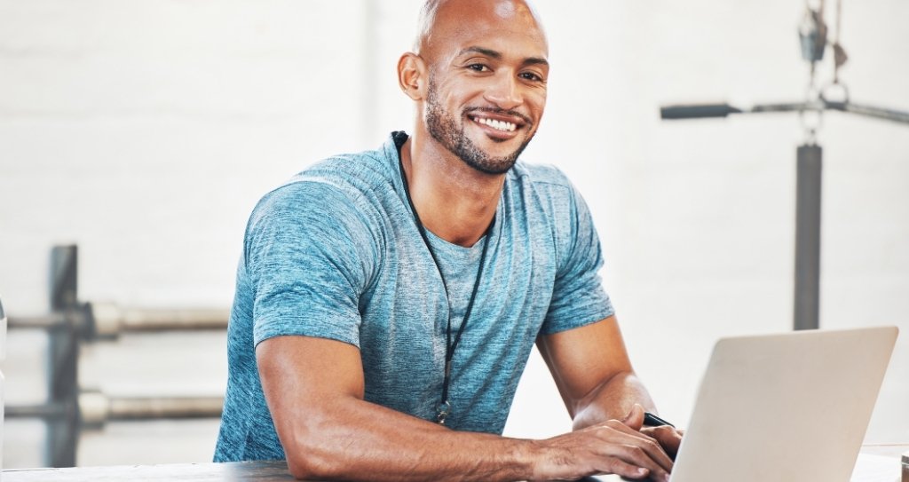 Dono de academia usando notebook para gerenciar cobranças com Pix Automático no Site Cielo. Essa modalidade do sistema Pix é ideal para negócios com pagamentos recorrentes.