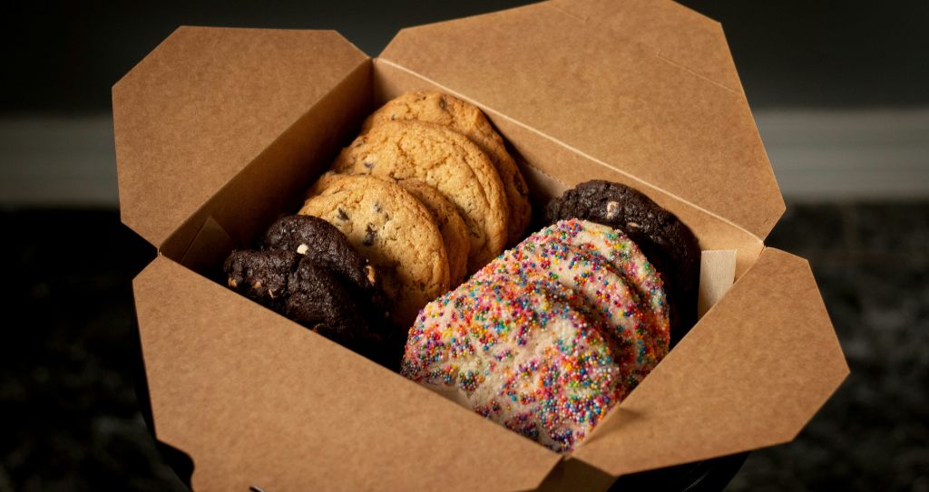 Caixa com cookies coloridos e sabores diversos, ideal para quem busca ideias de doces para vender com boa margem de lucro.