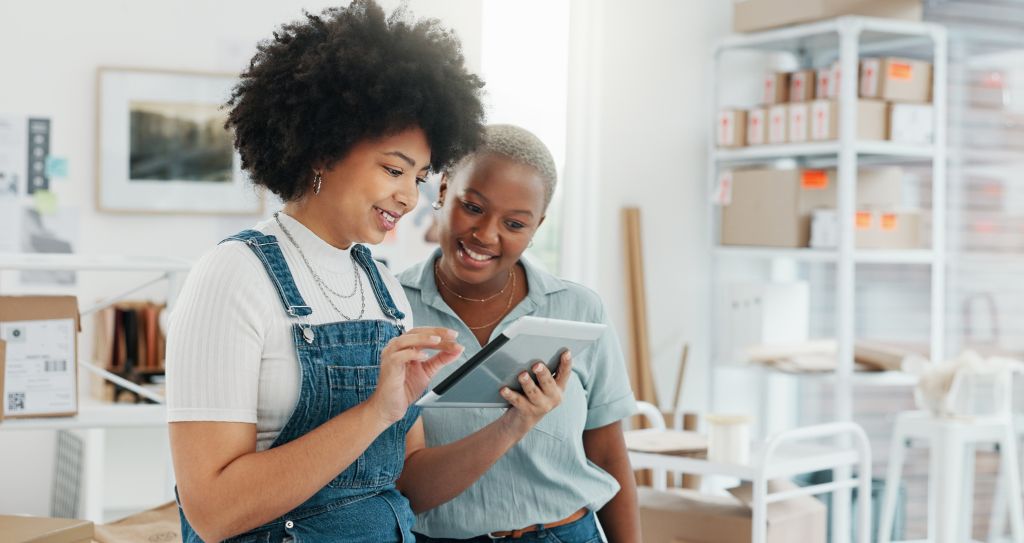 Empreendedoras analisando vendas com tablet, ilustrando o impacto dos juros simples e composto nas decisões do dia a dia.