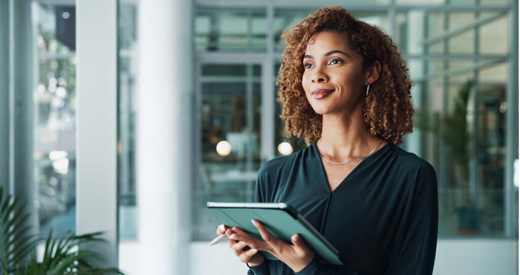 Mulher empreendedora segurando ferramenta digital, enquanto pensa sobre a aplicação da prateleira infinita no seu negócio.