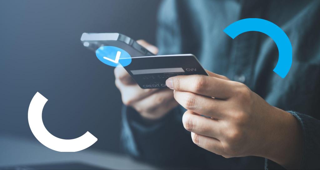 Pessoa segurando cartão de crédito com a mão esquerda, enquanto utiliza o celular com a mão direita par realizar pagamentos digitais com segurança.