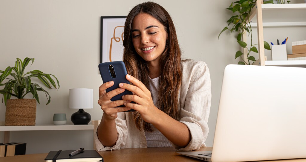 Mulher sorrindo enquanto gerencia seu negócio pelo App Cielo Gestão, conferindo a taxa MDR aplicada ao seu negócio.