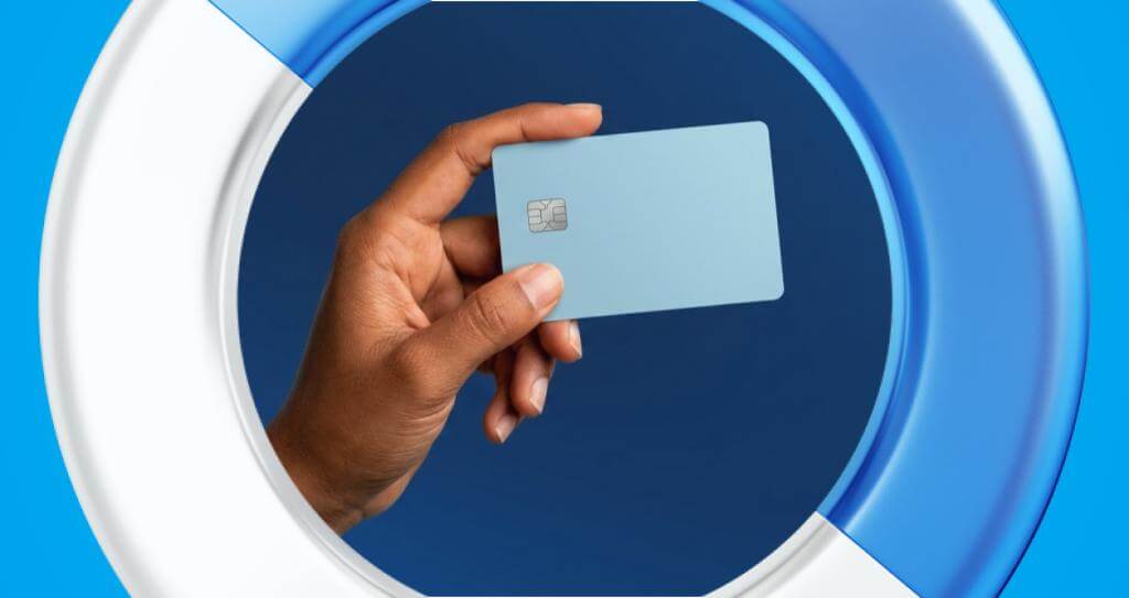 Detalhe de mão segurando cartão de crédito azul.