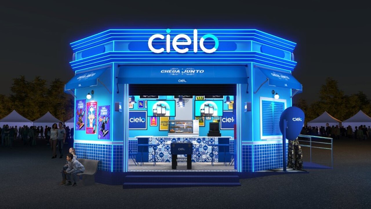 Estande da Cielo para o Lollapalooza, com iluminação em azul e identidade visual inspirada em um boteco brasileiro contemporâneo. O espaço destaca o logo da Cielo, ativações interativas, telas digitais e elementos de tecnologia de pagamentos, integrando cultura, música e meios de pagamento em uma experiência de marca no Lollapalooza Brasil 2026.
