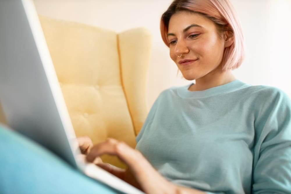 Empreendedora sorrindo ao usar notebook para comparar maquininhas com menor taxa do mercado.