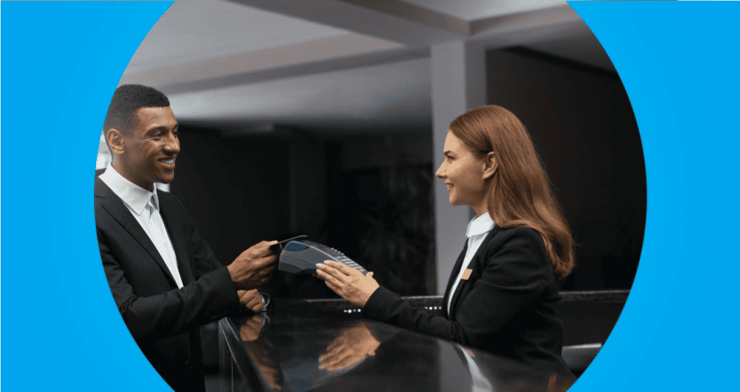 recepcionista de hotel oferece maquininha para hóspede realizar pagamento no check-in.