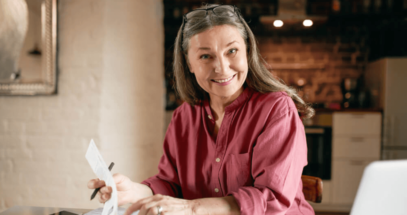 Empreendedora analisando recebíveis com documentos e notebook para antecipar pagamentos com a Cielo.