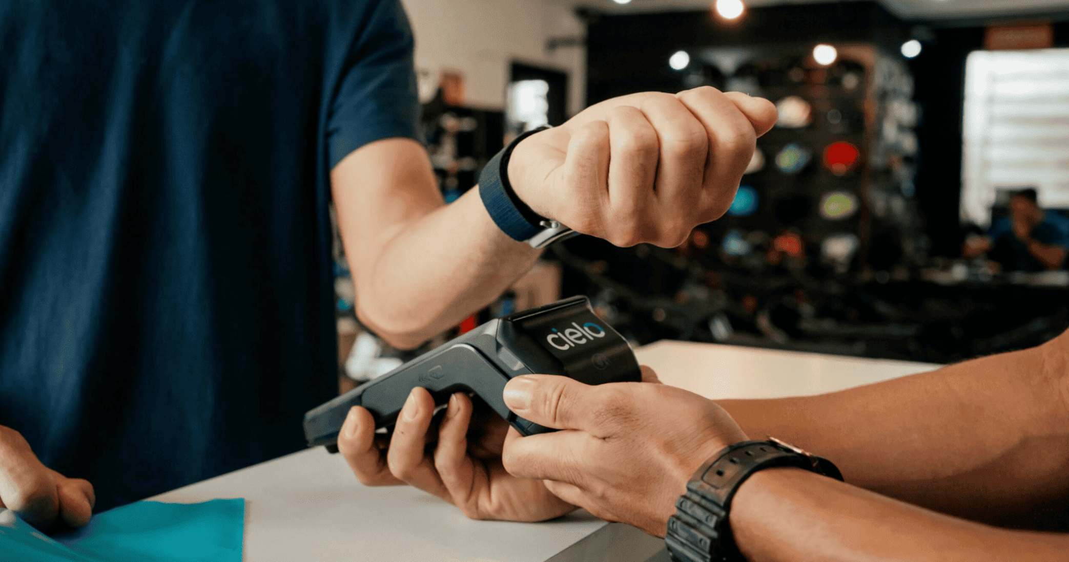 cliente realiza pagamento por aproximação com smartwatch em maquininha cielo em loja esportiva.