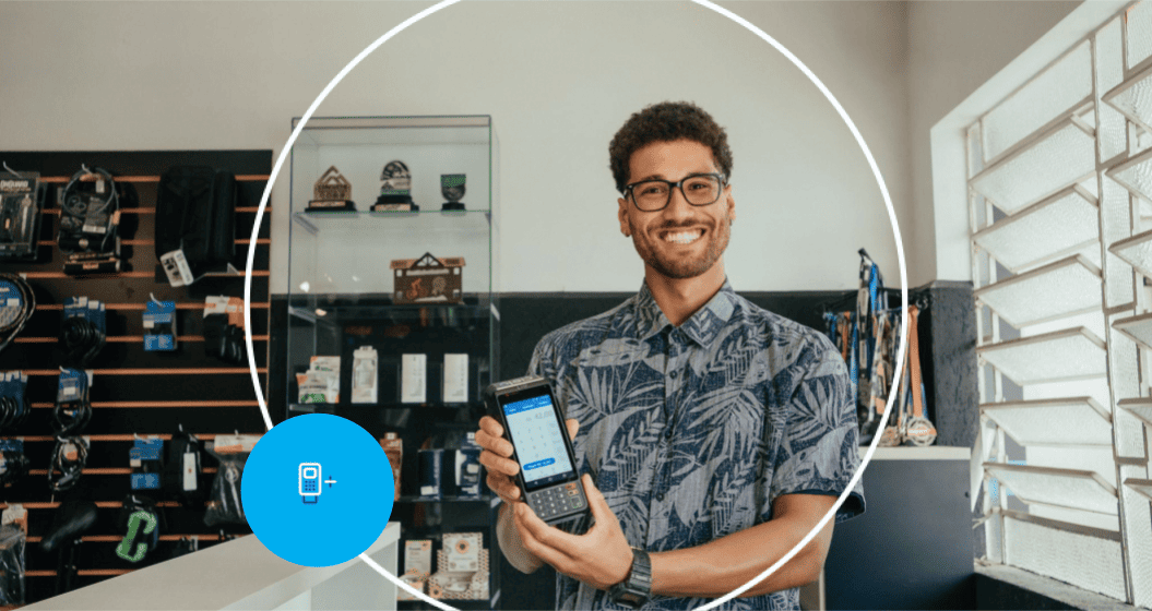 Empreendedor em sua loja sorrindo ao mostrar sua maquininha Cielo.