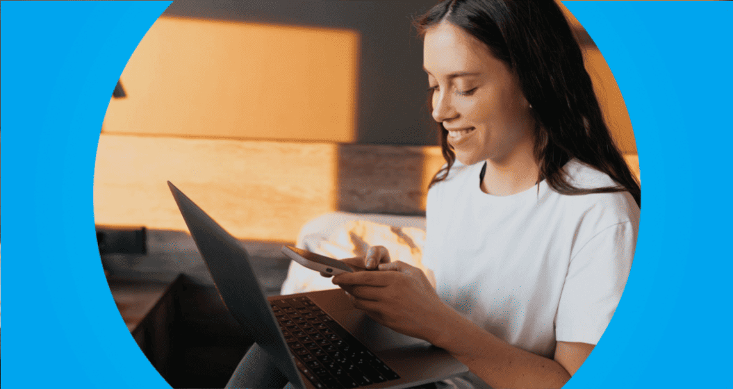 empreendedora fazendo pagamento invisível no celular, em frente a um notebook.