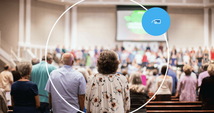 fiéis de costas em culto com telão ao fundo e ícone de pagamento digital.