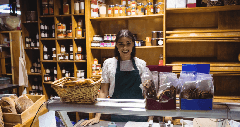 Mulher em uma loja, observando um balcão repleto de alimentos variados.