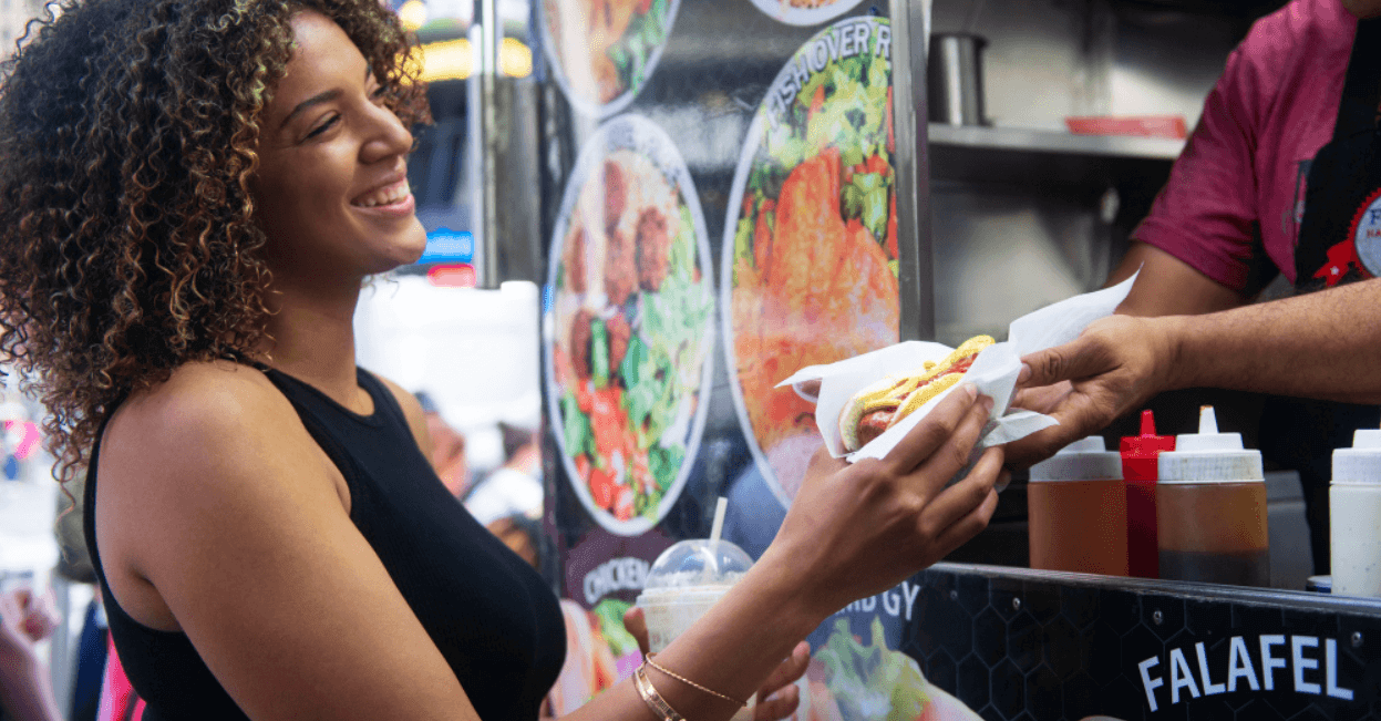 Um homem entrega comida a uma mulher em um food truck.