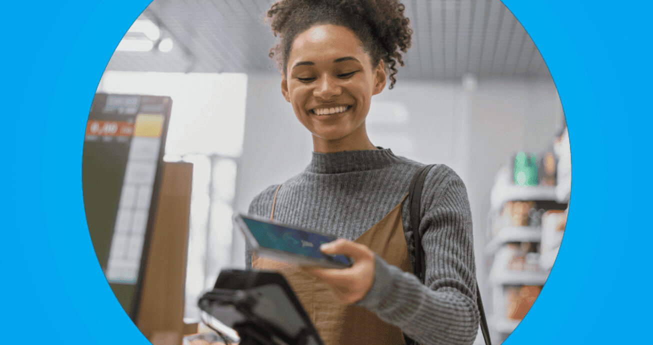 mulher sorrindo ao aproximar cartão de crédito na maquininha em caixa de supermercado.