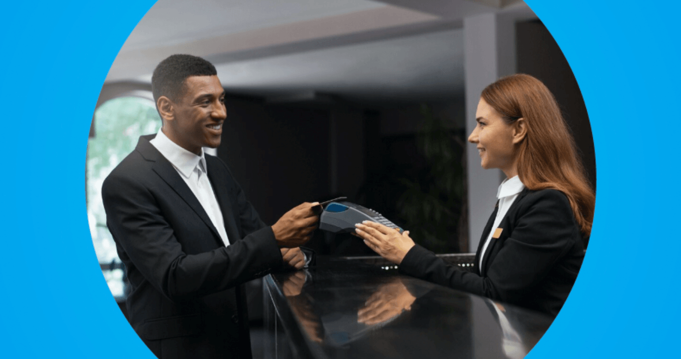 Empreendedora recebendo pagamento de hóspede com maquininha em hotel.