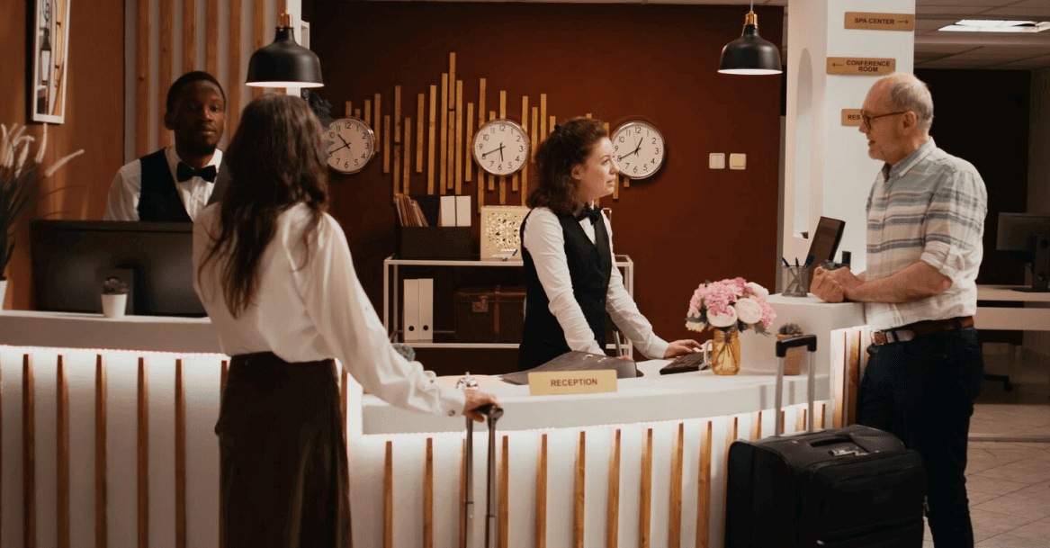 hóspedes com malas sendo atendidos por recepcionistas no balcão de check-in de hotel.