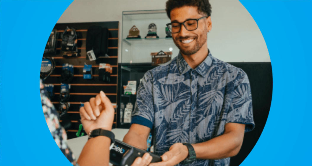 Um atendente sorridente entregando uma maquininha de cartão para uma cliente em um ambiente comercial, sugerindo um atendimento amigável e uma transação de pagamento.