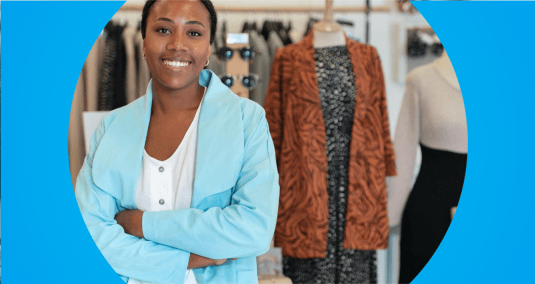 Mulher em pé diante de um cabideiro com várias roupas penduradas.