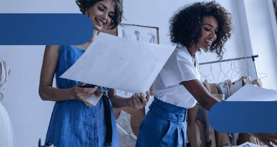 Duas mulheres vestindo azul trabalham juntas em um projeto, demonstrando foco e colaboração.