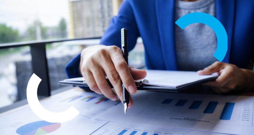 Pessoa analisando relatórios com gráficos e indicadores de desempenho, utilizando anotações para apoiar a tomada de decisões financeiras e estratégicas.