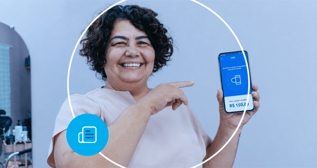 Mulher mostra a tela de um smartphone com uma solução de pagamento da Cielo e aponta para o valor exibido na tela.