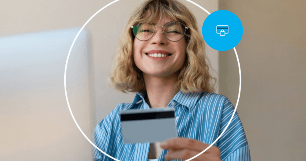 Pessoa sorrindo enquanto segura um cartão bancário, representando pagamento digital e compras online com segurança.