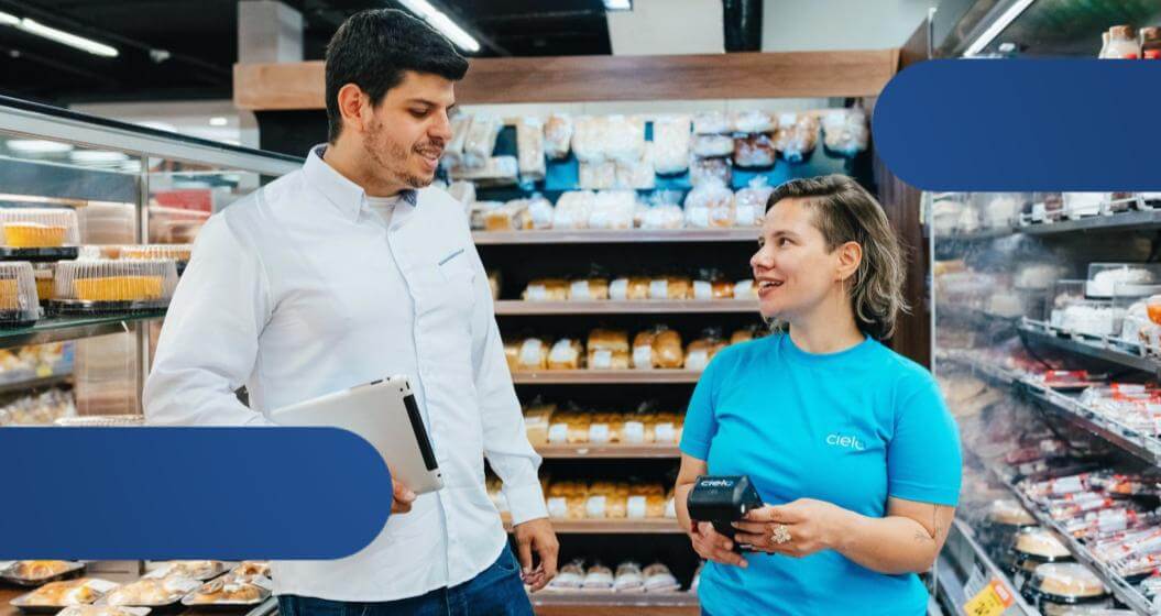 Representante da Cielo apresenta soluções de pagamento para gerente de supermercado durante atendimento no estabelecimento.