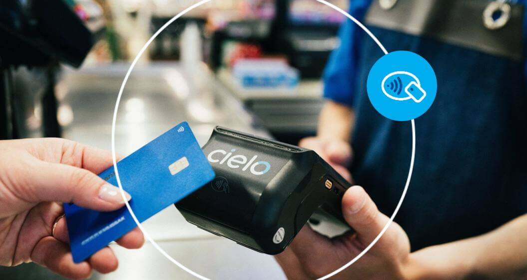 Pessoa realizando um pagamento por aproximação com cartão de crédito em uma maquininha Cielo durante uma compra em estabelecimento comercial.