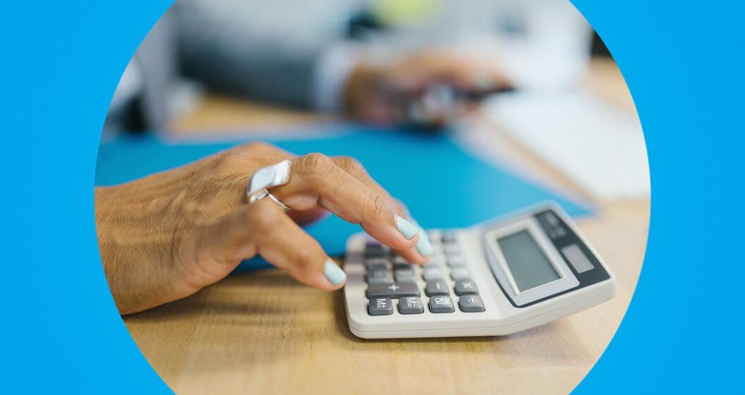 mão feminina calculando juros em uma calcularadora.