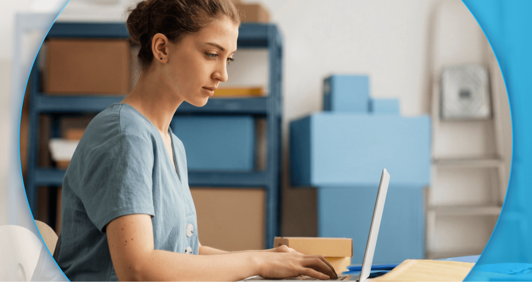 Mulher jovem de pele clara e cabelo preso digita concentrada em um notebook em um estoque. Ela veste blusa azul-acinzentada e está cercada por prateleiras e caixas de papelão, em um enquadramento circular sobre fundo azul.